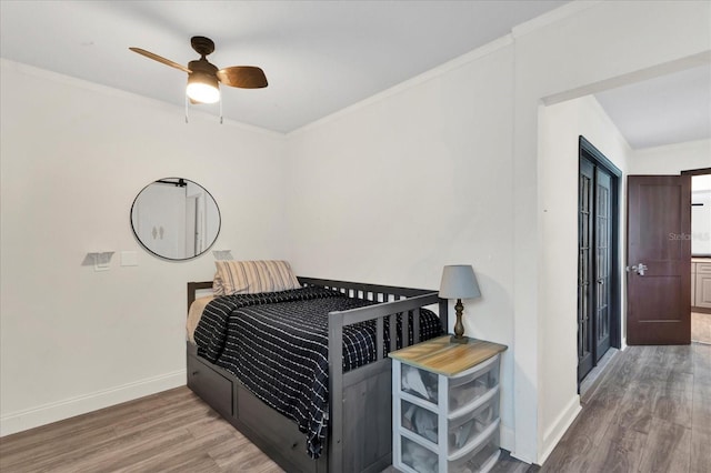 bedroom featuring ornamental molding, a ceiling fan, baseboards, and wood finished floors