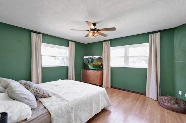 bedroom featuring light wood-style floors, a textured ceiling, and a ceiling fan