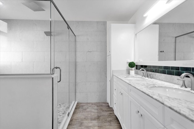 bathroom with double vanity, a stall shower, and a sink