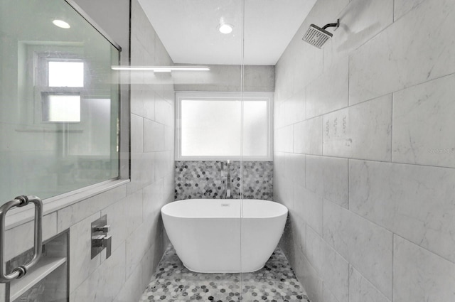 full bathroom featuring a freestanding tub, tile patterned flooring, tile walls, and tiled shower