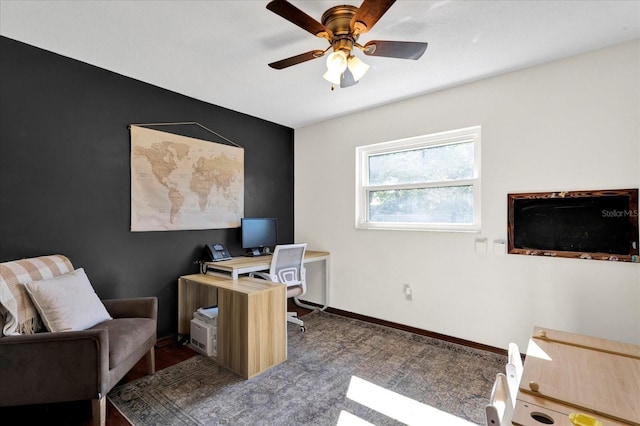 carpeted office space featuring ceiling fan and baseboards