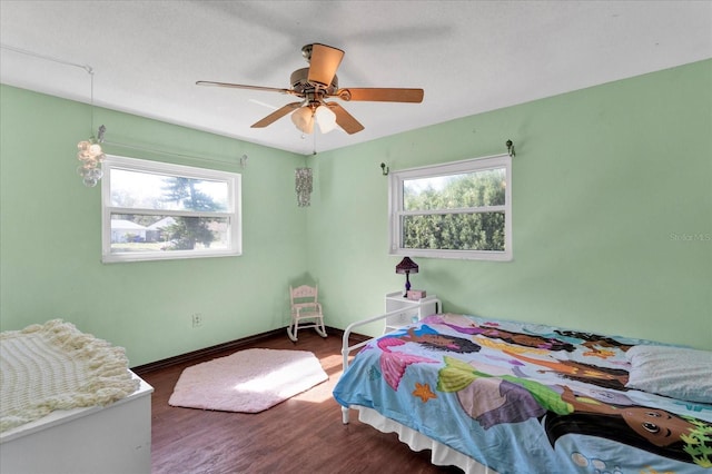 bedroom with baseboards, multiple windows, a ceiling fan, and wood finished floors