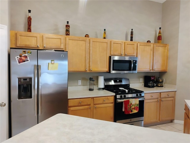 kitchen with light tile patterned floors, appliances with stainless steel finishes, light brown cabinets, and light countertops