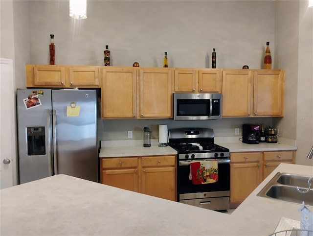 kitchen with a sink, stainless steel appliances, light brown cabinetry, and light countertops