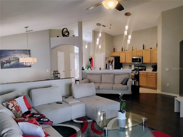 living area featuring baseboards, ceiling fan, wood finished floors, arched walkways, and high vaulted ceiling