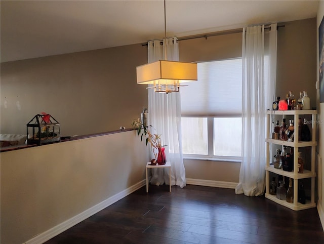 unfurnished dining area with baseboards and dark wood-style flooring