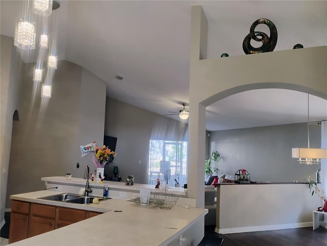 kitchen with a ceiling fan, arched walkways, a sink, light countertops, and open floor plan