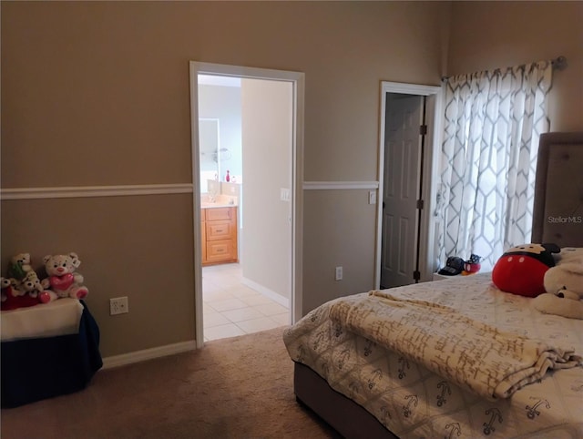 bedroom featuring baseboards, light carpet, and ensuite bathroom