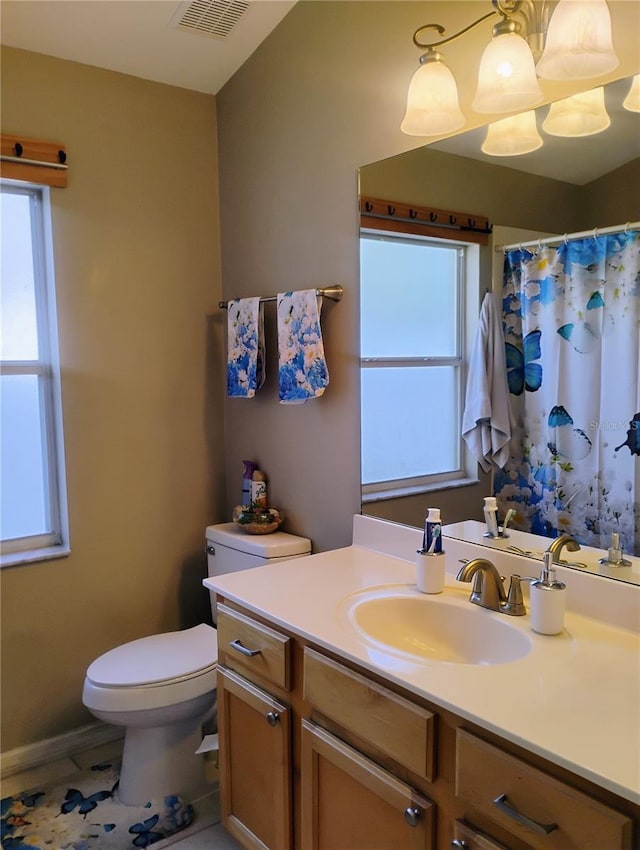 full bathroom featuring vanity, toilet, visible vents, and a wealth of natural light