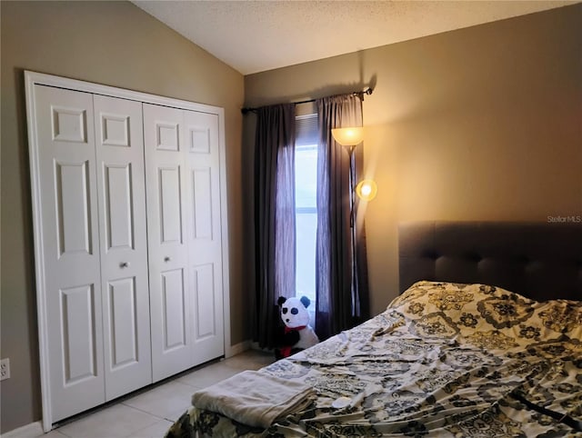 bedroom with light tile patterned floors, a closet, lofted ceiling, and a textured ceiling