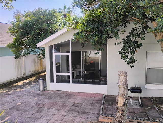 view of patio with fence and a sunroom