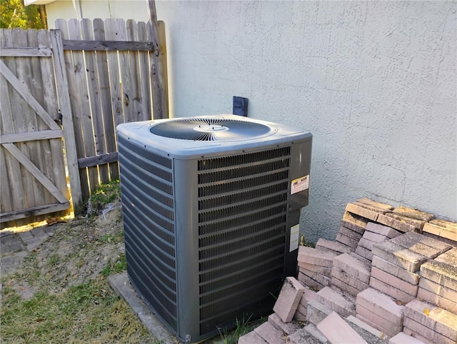 details featuring stucco siding, cooling unit, and fence