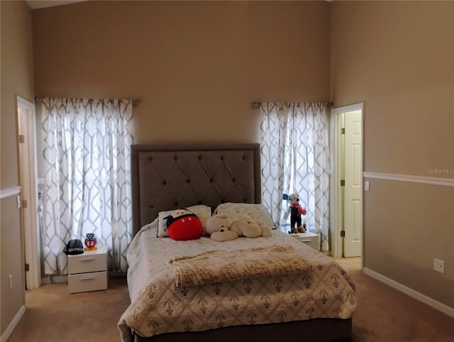 bedroom featuring baseboards, light carpet, and a towering ceiling