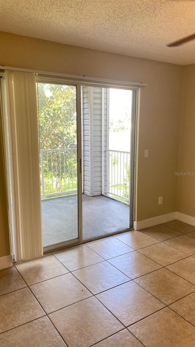 entryway with a textured ceiling, light tile patterned flooring, and baseboards