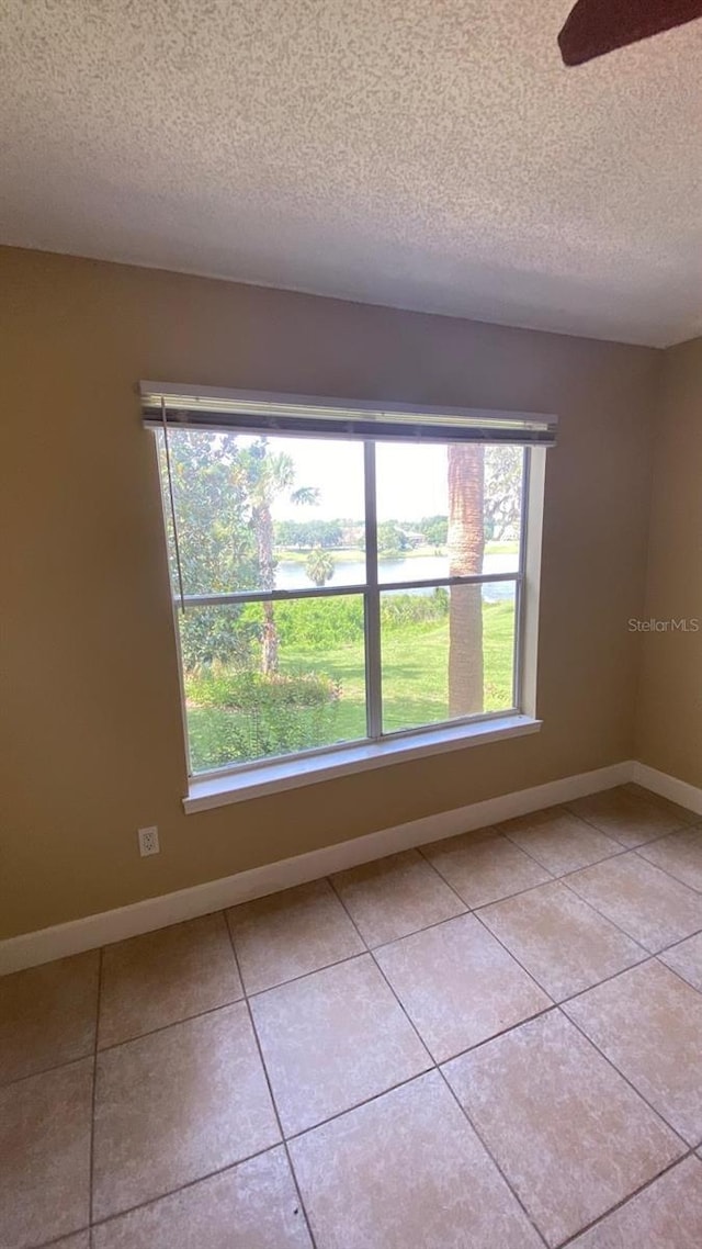 spare room with a ceiling fan, a textured ceiling, baseboards, and light tile patterned floors