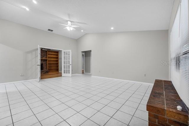 unfurnished living room featuring light tile patterned floors, lofted ceiling, visible vents, a brick fireplace, and ceiling fan