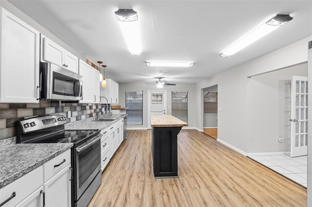 kitchen featuring wood counters, white cabinets, appliances with stainless steel finishes, light wood-type flooring, and pendant lighting