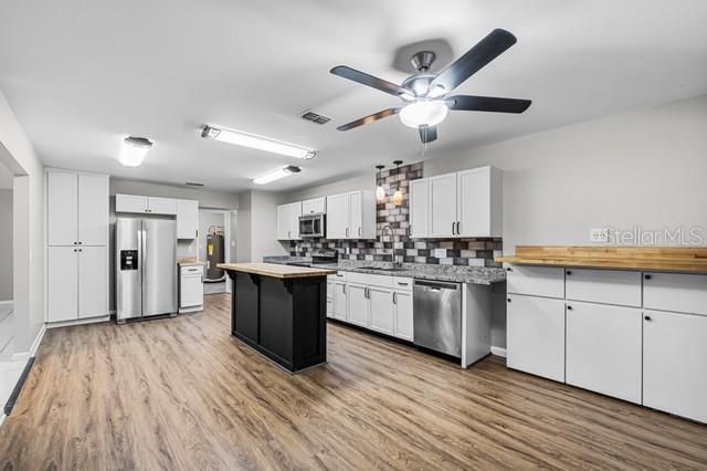 kitchen with a center island, light countertops, appliances with stainless steel finishes, light wood-style floors, and white cabinets