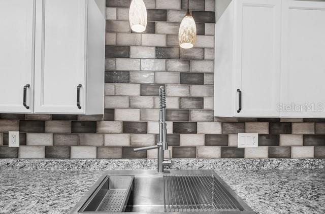 details featuring pendant lighting, light stone counters, a sink, and white cabinets