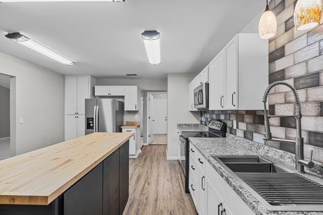 kitchen featuring stainless steel appliances, tasteful backsplash, hanging light fixtures, white cabinetry, and a sink