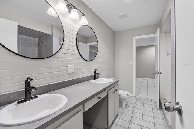 full bath featuring double vanity, tile patterned flooring, toilet, and a sink