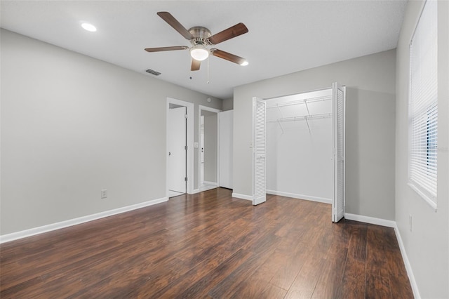 unfurnished bedroom featuring ceiling fan, dark wood-type flooring, visible vents, baseboards, and a closet