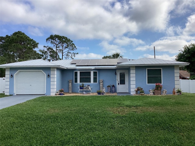 ranch-style home with stucco siding, an attached garage, a front yard, roof mounted solar panels, and metal roof