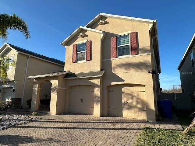 traditional home featuring a garage, decorative driveway, and stucco siding