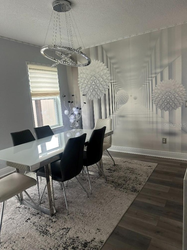 dining space with a textured ceiling, baseboards, and wood finished floors