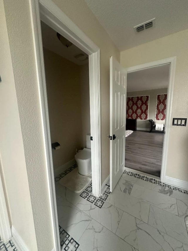 bathroom featuring marble finish floor, baseboards, visible vents, and a textured ceiling