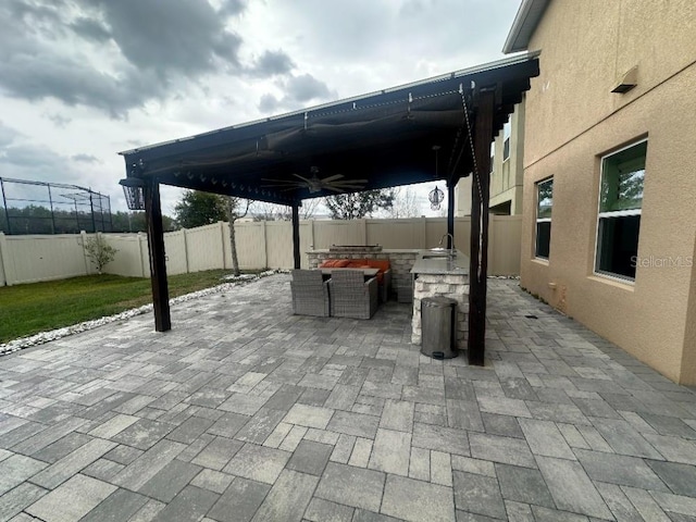 view of patio / terrace with an outdoor kitchen, a fenced backyard, and a ceiling fan