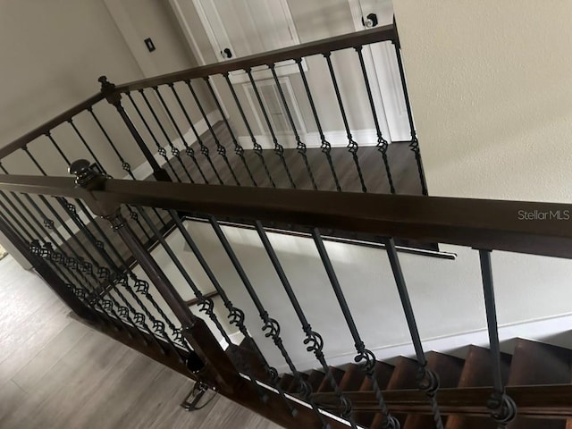 staircase featuring wood finished floors and a textured wall