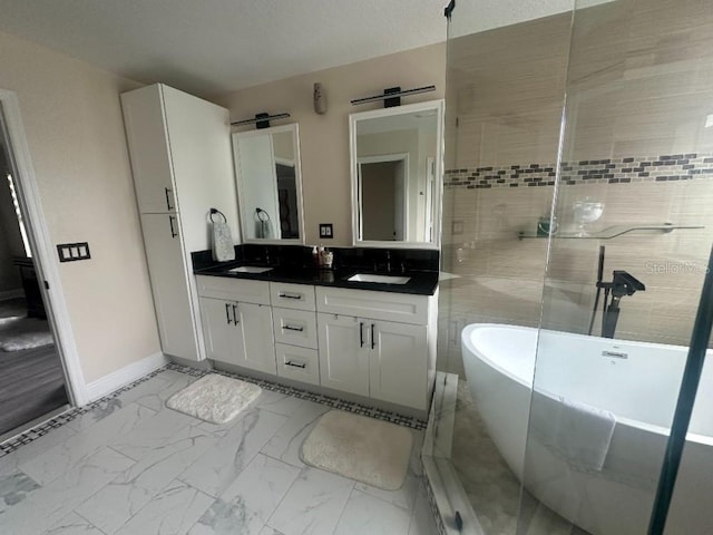 bathroom with marble finish floor, a freestanding tub, a sink, and double vanity