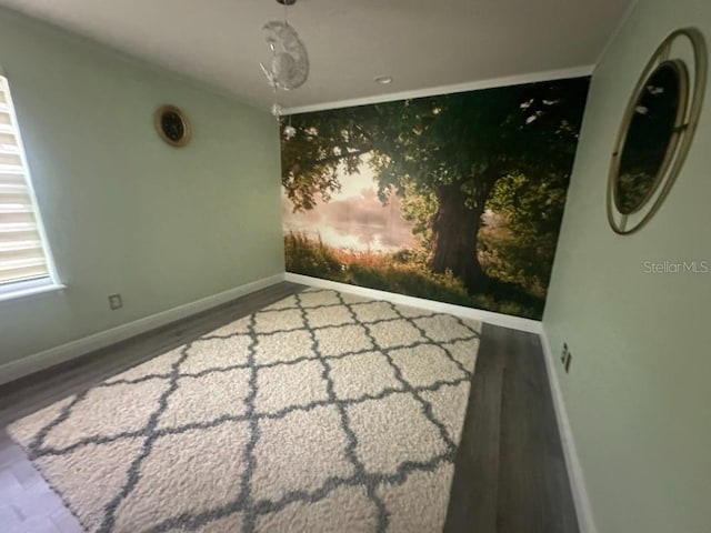 empty room featuring an accent wall, baseboards, and wood finished floors