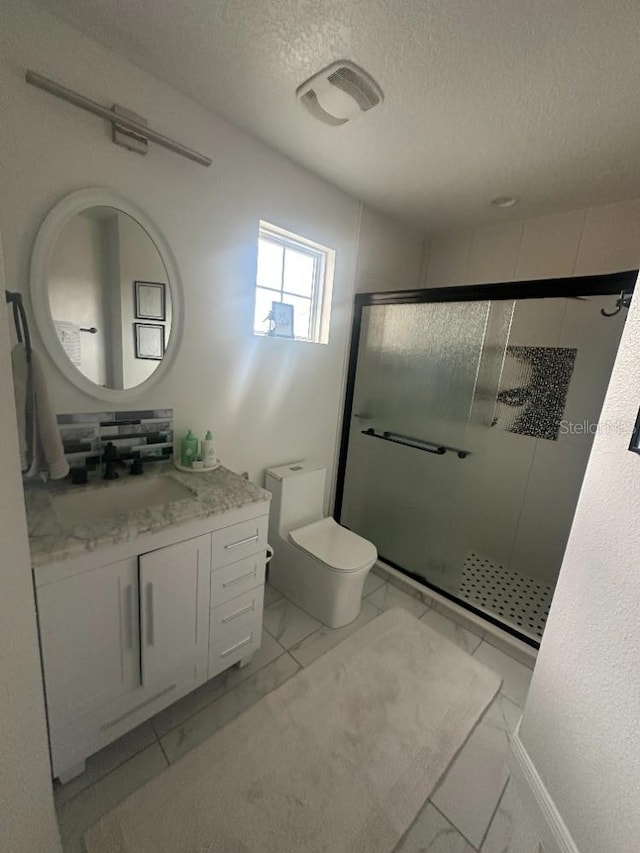 bathroom featuring toilet, marble finish floor, vanity, and a stall shower