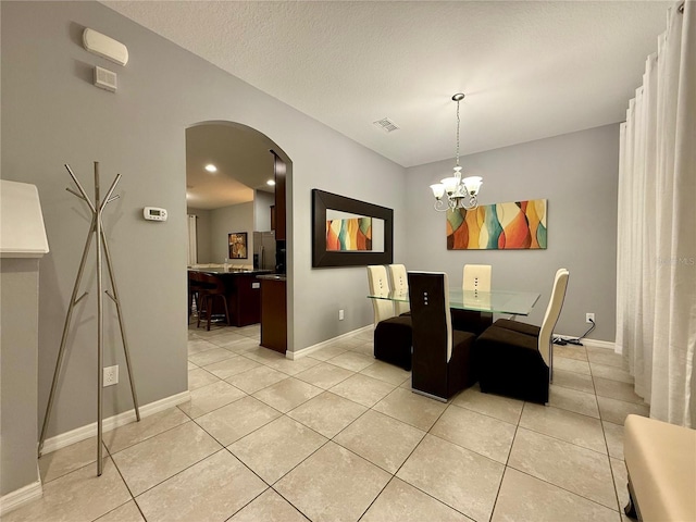 dining space featuring light tile patterned floors, baseboards, arched walkways, and a notable chandelier