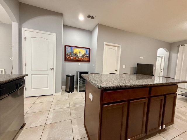 kitchen with arched walkways, light tile patterned floors, visible vents, a kitchen island, and dishwasher