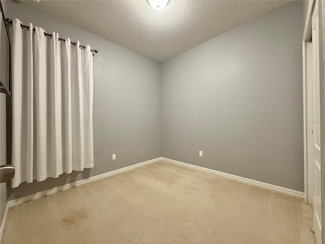 carpeted empty room featuring a textured ceiling and baseboards