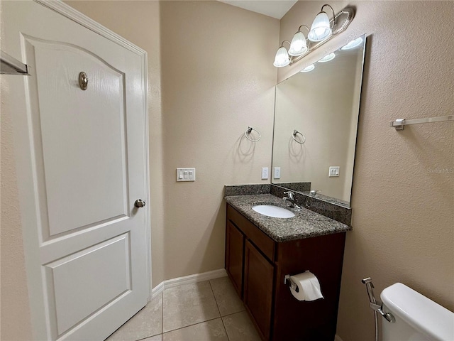 bathroom with tile patterned flooring, baseboards, vanity, and toilet