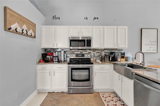 kitchen featuring white cabinets, appliances with stainless steel finishes, backsplash, and a sink