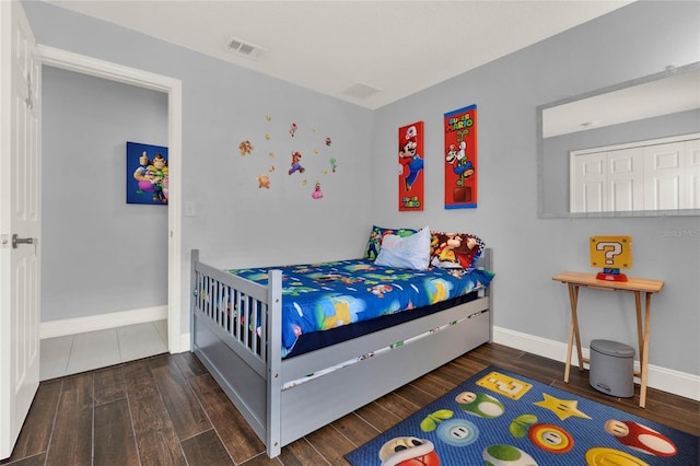 bedroom featuring wood finished floors, visible vents, and baseboards