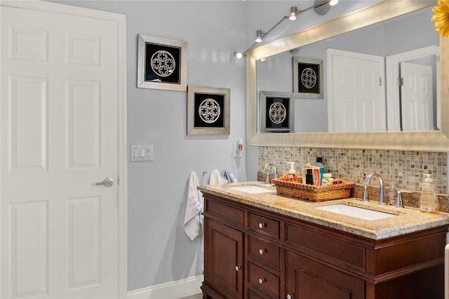 bathroom with tasteful backsplash, a sink, baseboards, and double vanity