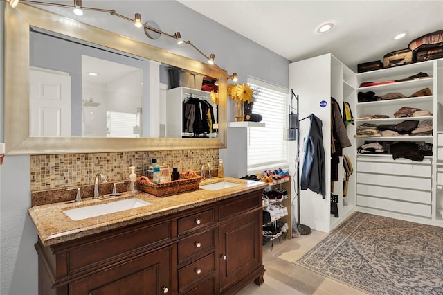 full bathroom featuring tasteful backsplash, a walk in closet, and a sink