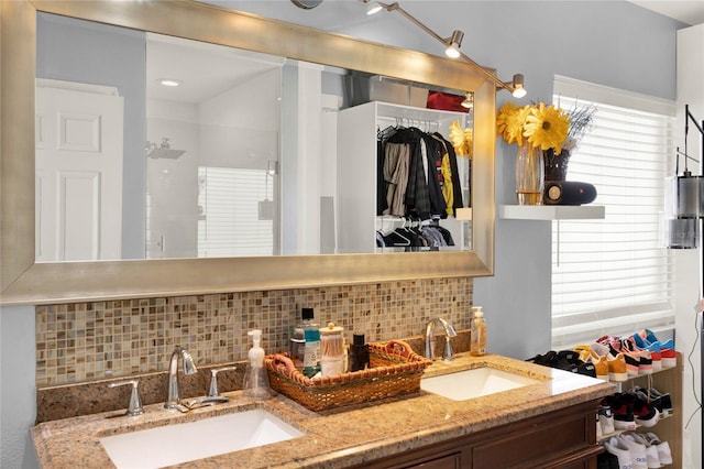 bathroom featuring double vanity, a shower stall, decorative backsplash, and a sink