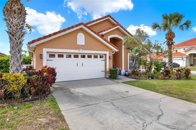 mediterranean / spanish-style home with a garage, concrete driveway, stucco siding, a tiled roof, and a front yard