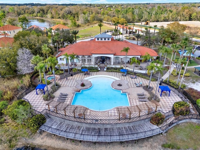 pool with a forest view, fence, and a patio