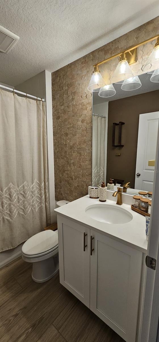 803 Longboat Dr, Davenport, FL 33896 - full bathroom featuring wood finished floors, vanity, a textured ceiling, and a shower with curtain