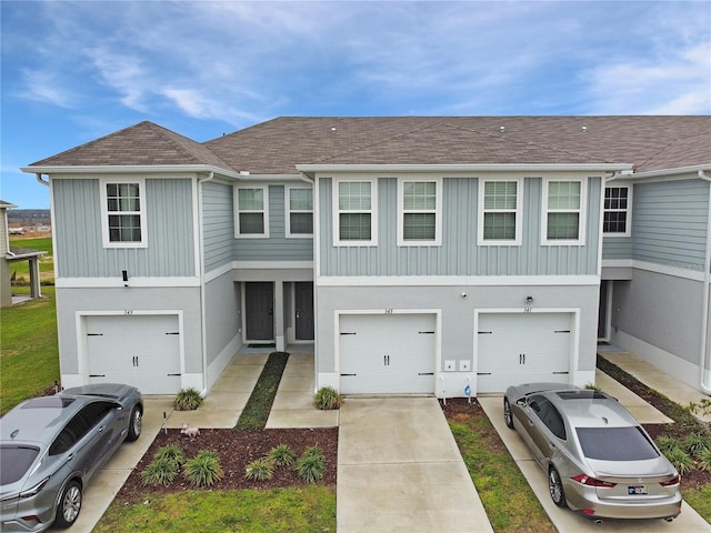 multi unit property featuring a garage, driveway, a shingled roof, and stucco siding