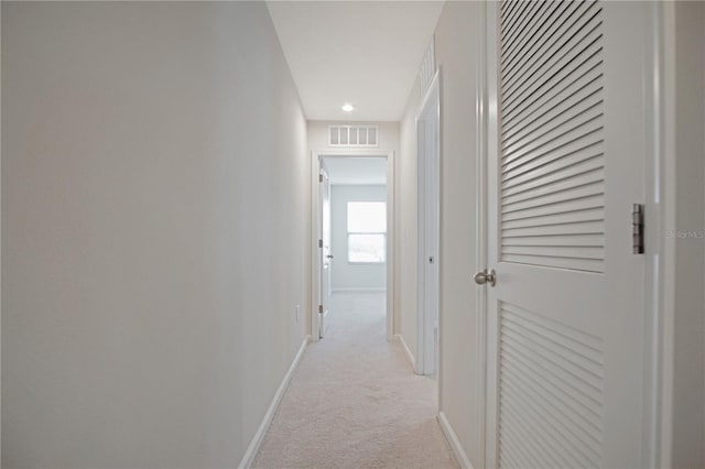 hall featuring light colored carpet, visible vents, and baseboards