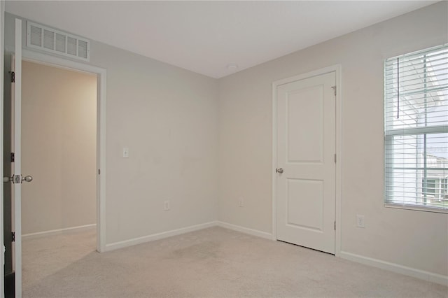 unfurnished room with baseboards, visible vents, and light colored carpet